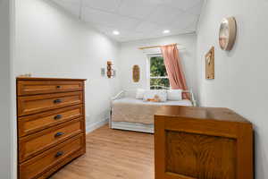Bedroom with light wood-style floors, recessed lighting, and a drop ceiling