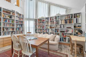 Library featuring wall of books, light wood look tile flooring, and plenty of natural light