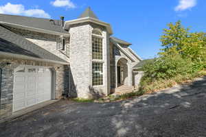 View of front of home with a shingled roof, brick siding, and driveway