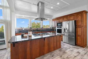 Gourmet kitchen with wood look tile floors, stainless steel appliances, recessed lighting, island exhaust hood, granite counters & wall of windows