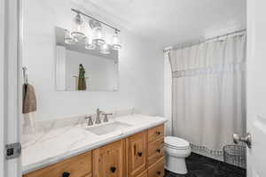 Full bath featuring vanity, a textured ceiling, and a tub/shower with curtain