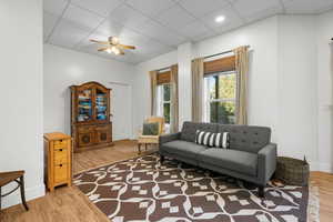 Family room with a drop ceiling, light wood-type flooring, and ceiling fan