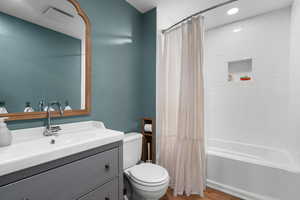 Full bathroom featuring shower/bath combination with curtain, vanity, and wood finished floors