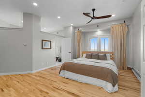 Master bedroom featuring hardwood floors, a baseboard radiator, recessed lighting, and ceiling fan and balcony