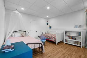 Bedroom with light wood-type flooring, a drop ceiling, and recessed lighting & exterior door