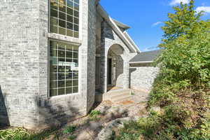 Covered doorway to property featuring brick siding