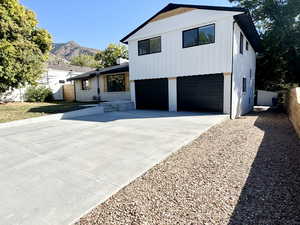View of front of house featuring brick siding, concrete driveway, an attached garage, a mountain view, and board and batten siding