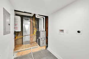 Utilities featuring electric panel, water heater, and heating unit