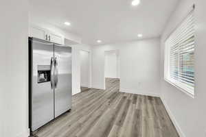 Kitchen featuring stainless steel refrigerator with ice dispenser, recessed lighting, light wood-style floors, and white cabinets