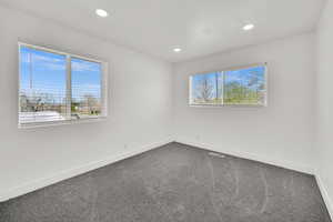 Empty room with dark carpet, healthy amount of natural light, and recessed lighting