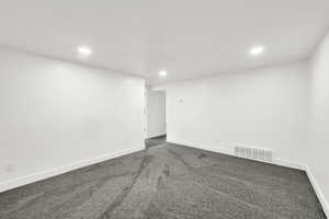 Spare room featuring dark colored carpet and recessed lighting