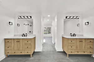 Bathroom featuring a stall shower, two vanities, recessed lighting, and dark tile patterned flooring