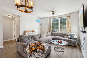 Living room with a chandelier, wood finished floors, and ceiling fan