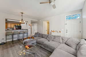 Living room featuring a chandelier, luxury vinyl floors, and a ceiling fan