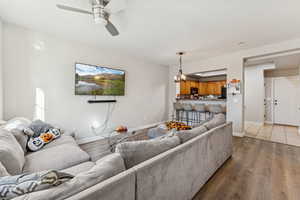 Living room with a chandelier, wood finished floors, and ceiling fan