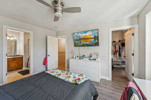 Bedroom with a walk in closet, a ceiling fan, luxury vinyl flooring, and ensuite bathroom