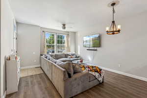 Living area featuring ceiling fan, luxury vinyl floors, and a chandelier