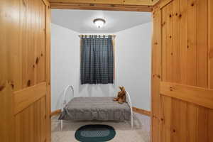 Carpeted bedroom featuring baseboards and wooden walls
