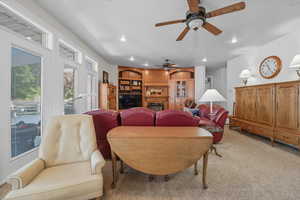 Carpeted living area featuring recessed lighting, a glass covered fireplace, and ceiling fan