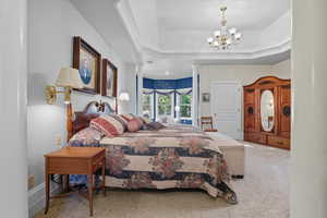 Primary Suite bedroom featuring a tray ceiling and a chandelier