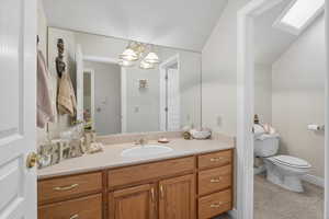 Bathroom with vanity, light tile patterned floors, a chandelier, and vaulted ceiling
