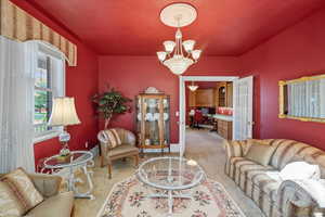 Living area featuring an office area, light carpet, and a chandelier