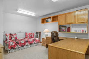Bedroom being used as an office featuring light carpet, a textured ceiling, and a desk
