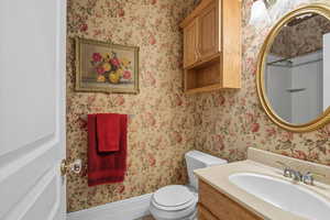 full bath with vanity and wallpapered walls
