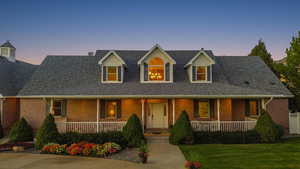 View of front of property with a porch, brick siding, and a shingled roof