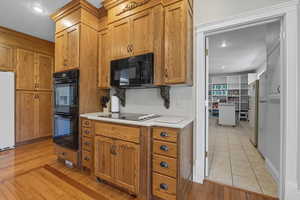Kitchen with light countertops, black appliances, light wood-type flooring, cabinetry, and recessed lighting