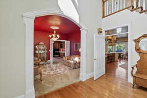 Entryway with arched walkways, hardwood / wood-style floors, a chandelier, and a towering ceiling