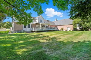 Back of property featuring a yard, brick, a wooden deck, and a chimney