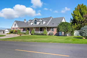 2 story house featuring covered porch, brick, roof with shingles, and a front lawn