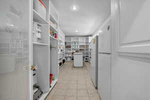 Massive Kitchen Pantry featuring light tile patterned floors and freestanding refrigerator