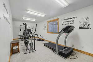 Bedroom being used as an exercise area with a textured ceiling and carpet flooring