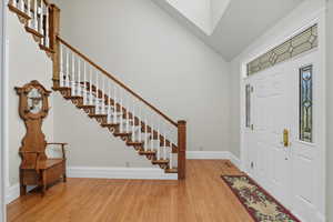 Entryway with light wood finished floors, stairs, and high vaulted ceiling