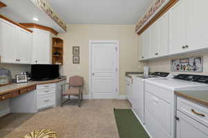 Laundry room with cabinet space, light carpet, a desk, and washer and dryer