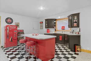 Kitchen featuring dark floors, light countertops, a kitchen island, and a breakfast bar