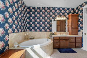 Primary Suite Bathroom featuring wallpapered walls, a garden tub, vanity, and a chandelier