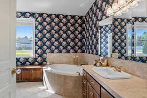 Primary Bathroom with a tub, vanity, and wallpapered walls
