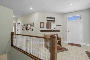 Back Entrance to the front of the home and the garage with a foyer with light tile patterned floors and recessed lighting