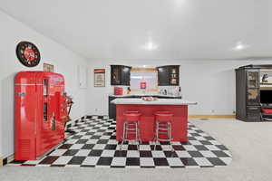 Indoor wet bar with light countertops, dark flooring, glass insert cabinets, and recessed lighting