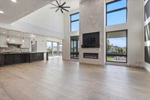 Living room with a high end fireplace, light wood finished floors, and a high ceiling for
