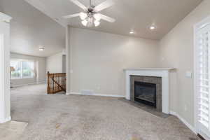 Unfurnished living room with light colored carpet, vaulted ceiling, ceiling fan, a tile fireplace, and recessed lighting