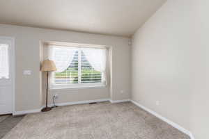 Carpeted empty room with baseboards and vaulted ceiling