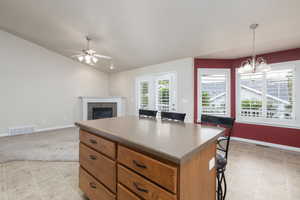 Kitchen with lofted ceiling, a center island, a breakfast bar, decorative light fixtures, and a fireplace