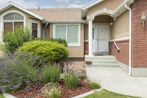 Property entrance featuring stucco siding, a shingled roof, and brick siding