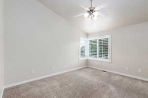 Carpeted empty room featuring lofted ceiling and a ceiling fan