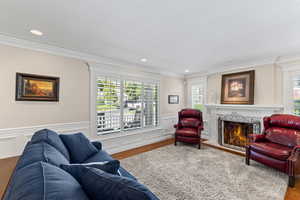 Living area featuring plenty of natural light, a high end fireplace, ornamental molding, recessed lighting, and wood finished floors