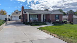 View of front of house featuring a porch, concrete driveway, brick siding, a chimney, and roof with shingles